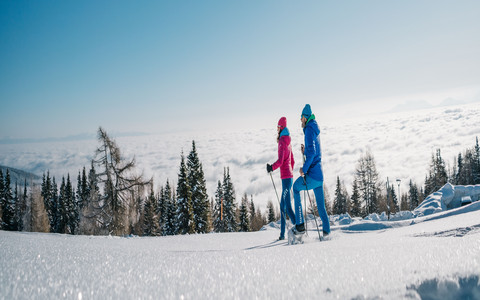 Mann und Frau beim Schneeschuhwandern durch eine verschneite Landschaft im Wellness- und Winterurlaub in Kärnten